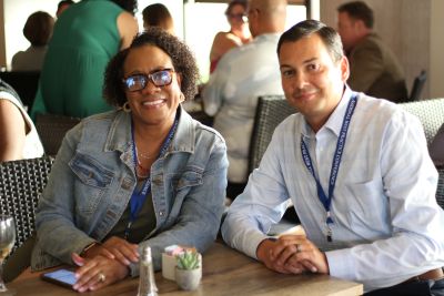 Two people sit at a table and smile at the 2024 National Prosecution Best Practices Conference. 