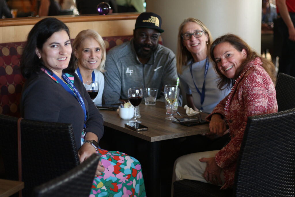 Five people gather around a table and smile at the 2024 National Prosecution Best Practices Conference.