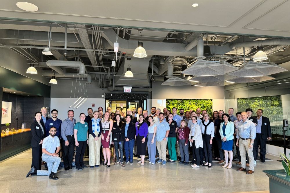 A large group of people stands together at the Microsoft PCE Hackathon event. 